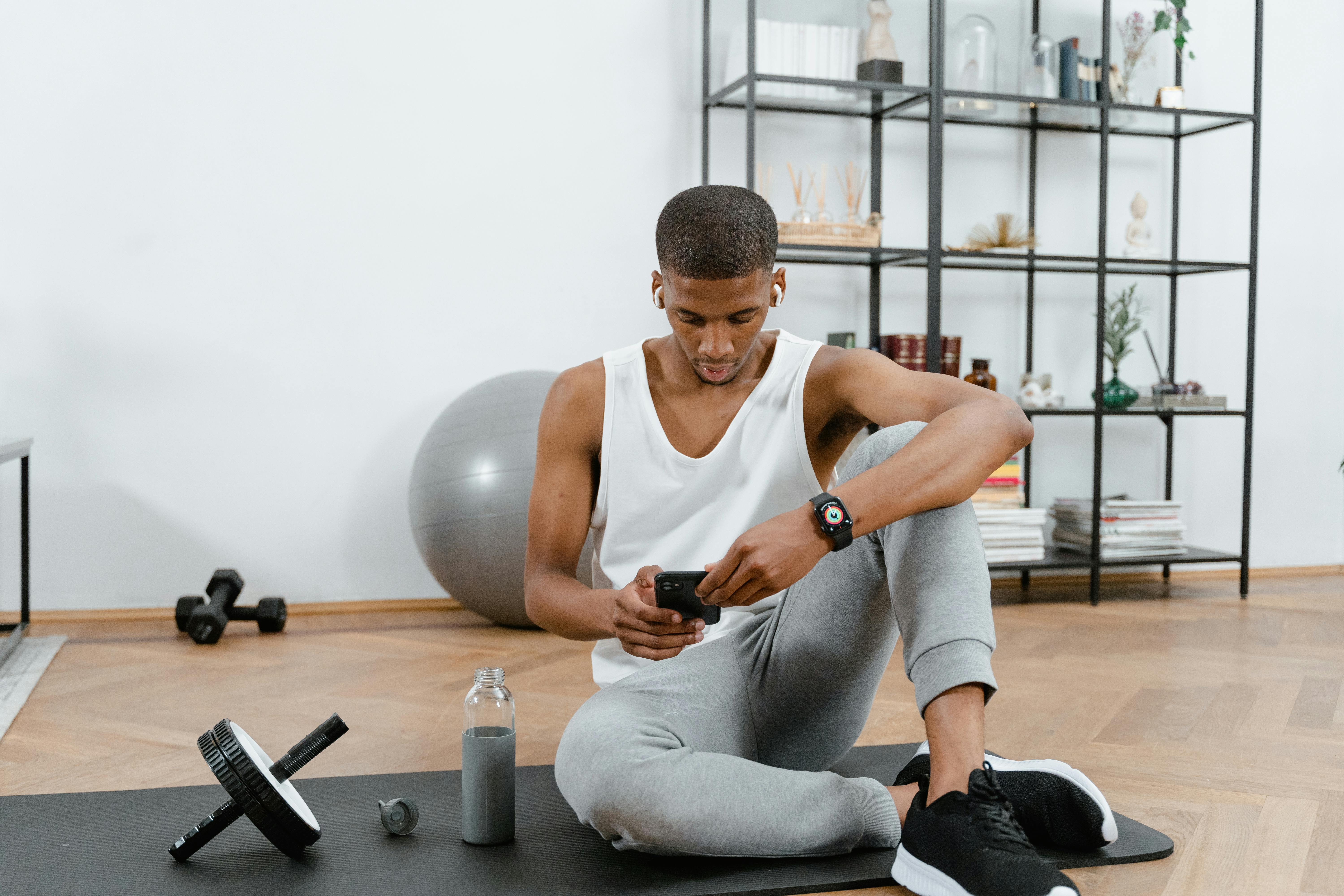Man on phone in home gym reviewing results